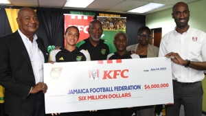 JFF president Michael Ricketts (left) accepts a symbolic cheque from ROJ&#039;s brand manager Andrei Roper, during a press conference at JFF&#039;s offices on Wednesday. Also in photo are Reggae Girlz Rebecca Spencer (second left) and Deneisha Blackwood (third right), as well as Head coach Lorne Donaldson and JFF&#039;s Head of women&#039;s football Elaine Walker-Brown.