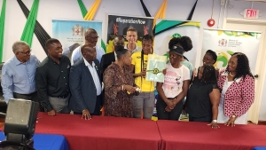 Latanya Wilson receiving keys to her new home from Minister Olivia Grange as members of her family, members of the sports ministry and representatives of the National Housing Trust and West Indies Home Contractors share in the emotional moment.